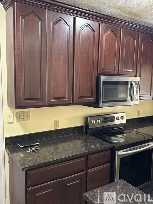 A kitchen with brown cabinets and a black countertop.