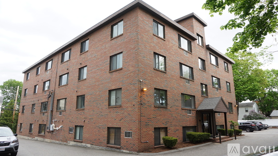 A red brick building with a black car parked in front.