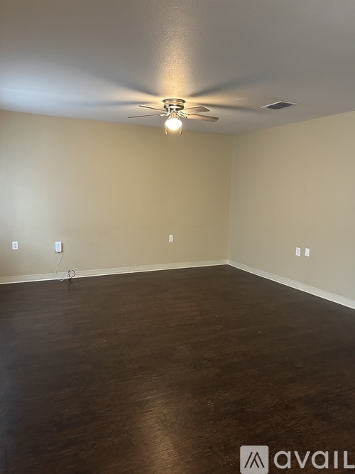 A room with a ceiling fan and wooden flooring.