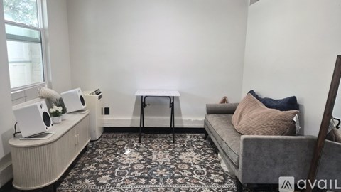 A living room with a grey couch and a black and white patterned rug.