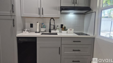 A kitchen with white cabinets and a black dishwasher.