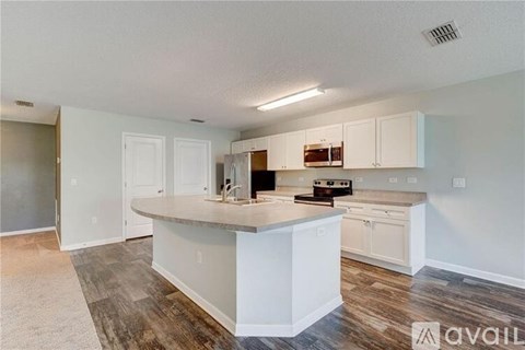 A kitchen with white cabinets and a wooden floor.