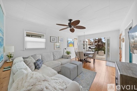 A living room with a white couch and a ceiling fan.