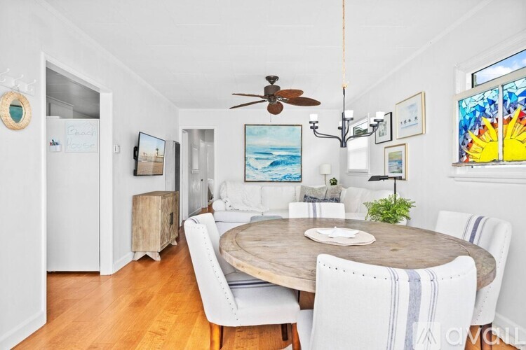 A dining room with a wooden table and white chairs.