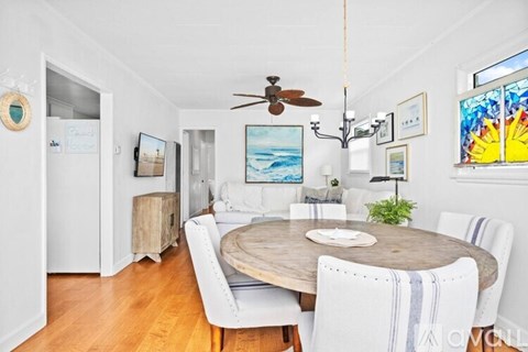 A dining room with a wooden table and white chairs.