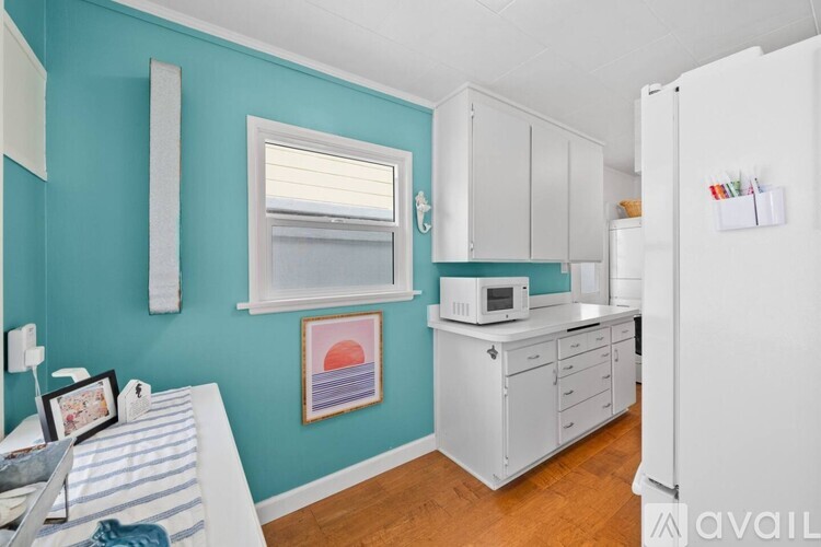 A kitchen with a white refrigerator and white cabinets.
