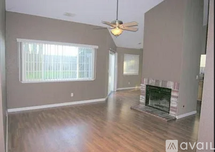 A living room with a fireplace and a ceiling fan.