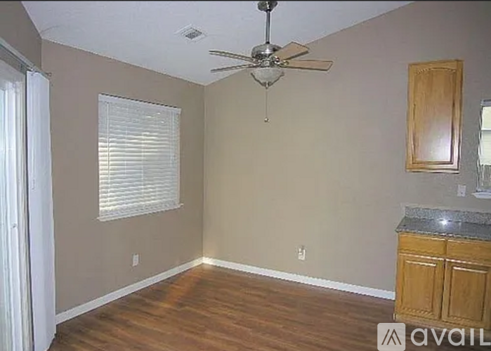 A room with a ceiling fan and a window with blinds.