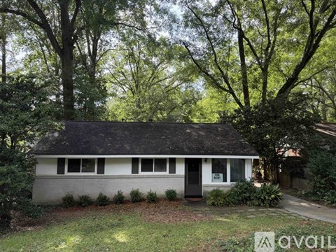 A small house with a black door and windows surrounded by trees.