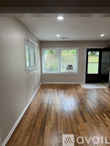 A room with wooden floors and a window with blinds.