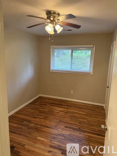 A room with wooden flooring and a ceiling fan with lights.