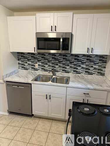 A kitchen with white cabinets and a black dishwasher.