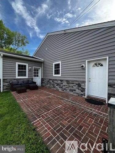 A grey house with a white door and a brick walkway.