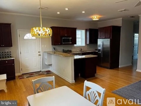 A kitchen with a white island and dark wood cabinets.