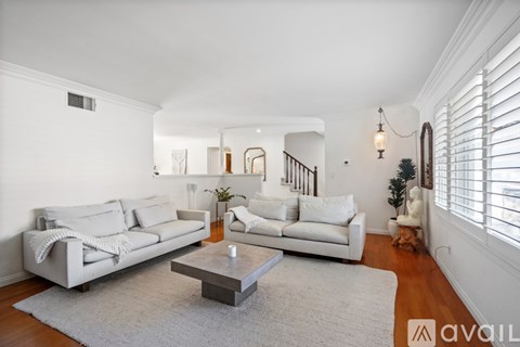 A living room with white furniture and a grey rug.