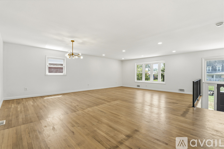 A spacious room with wooden flooring and a chandelier.