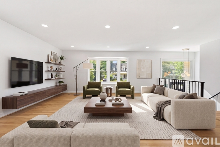 A modern living room with a large couch, a coffee table, and a television on the wall.