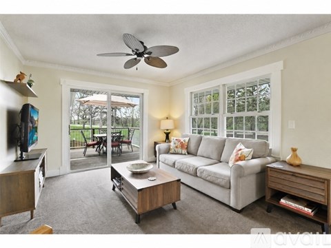 A living room with a grey couch and a ceiling fan.