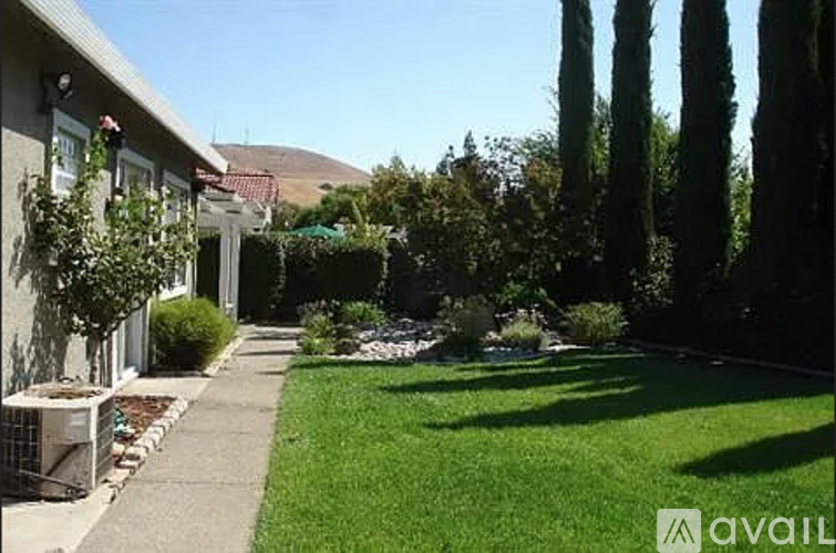 A house with a green lawn and trees in the background.