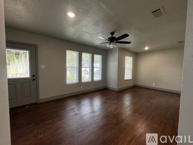 A spacious room with wooden floors and a ceiling fan.