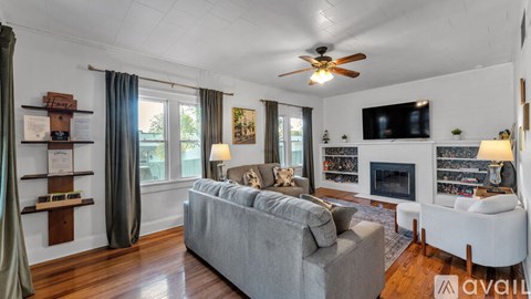 A living room with a grey couch and a fireplace.