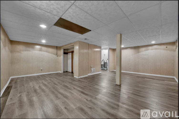 A spacious room with wooden flooring and a white ceiling.