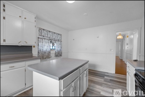 A kitchen with white cabinets and a grey countertop.
