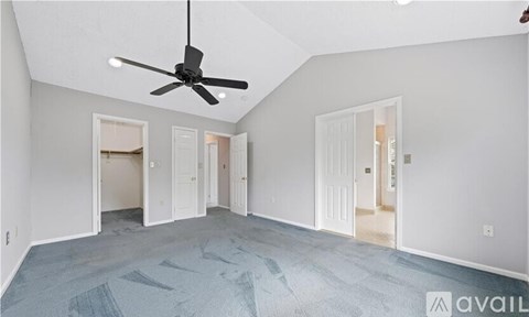 A spacious room with a ceiling fan and multiple doors.