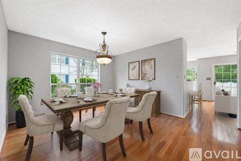 A dining room with a table set for six and a chandelier hanging from the ceiling.