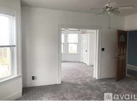 A room with a ceiling fan and a door leading to another room.