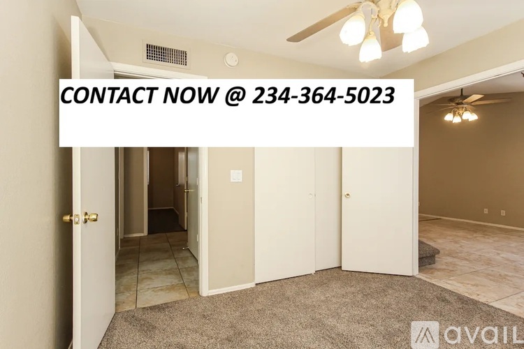 A room with a carpeted floor and a ceiling fan, with a door open to another room.