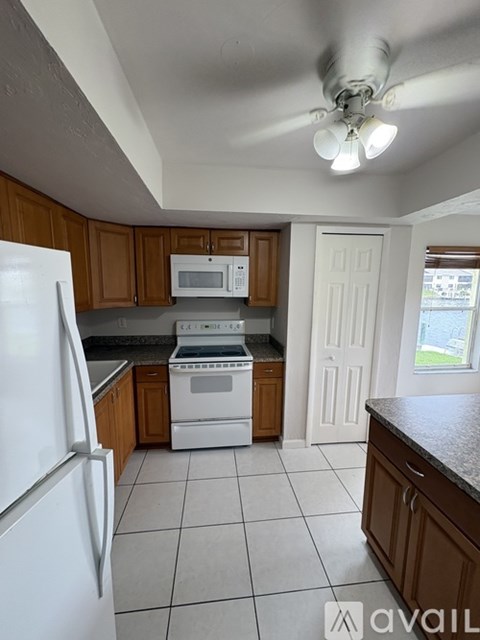 A kitchen with white appliances and brown cabinets.