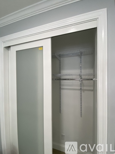 A white door is open to reveal a white closet with shelves.