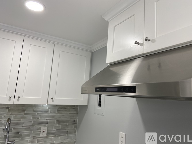A kitchen with white cabinets and a stainless steel range hood.