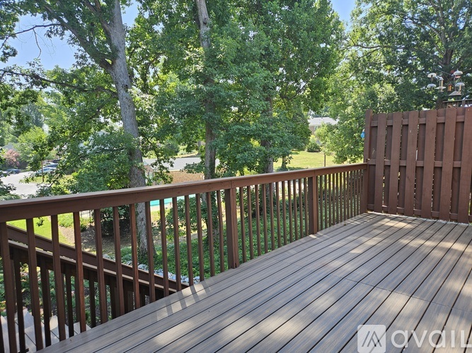 A wooden deck with a railing and trees in the background.