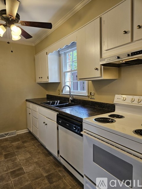 A kitchen with white cabinets and a black countertop.