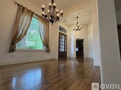A spacious room with wooden floors and a chandelier.