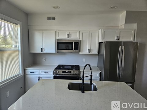 A kitchen with white cabinets and a stainless steel refrigerator.