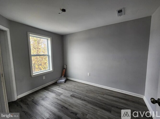 A room with grey walls and a window showing trees outside.