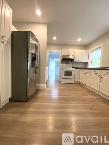 A kitchen with a refrigerator and wooden floors.
