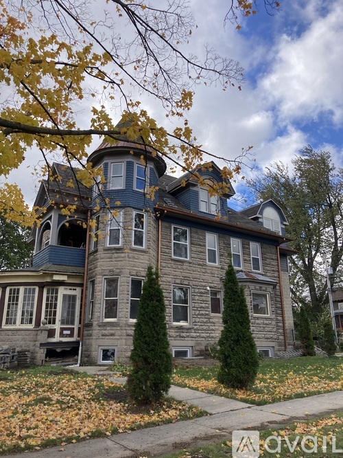 A large house with a tower and a wrap around porch.