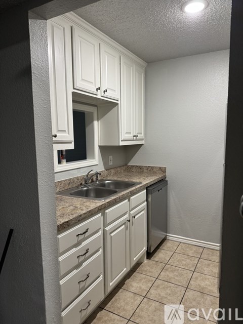 A kitchen with white cabinets and a granite countertop.