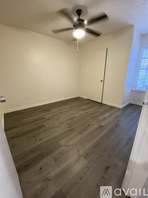 A room with a ceiling fan and wooden flooring.