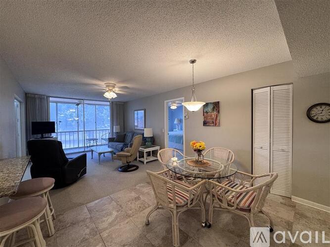A living room with a glass table and chairs, a sofa, and a television.