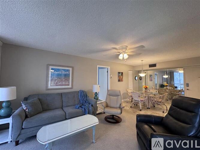 A living room with a grey couch, a white coffee table, and a ceiling fan.