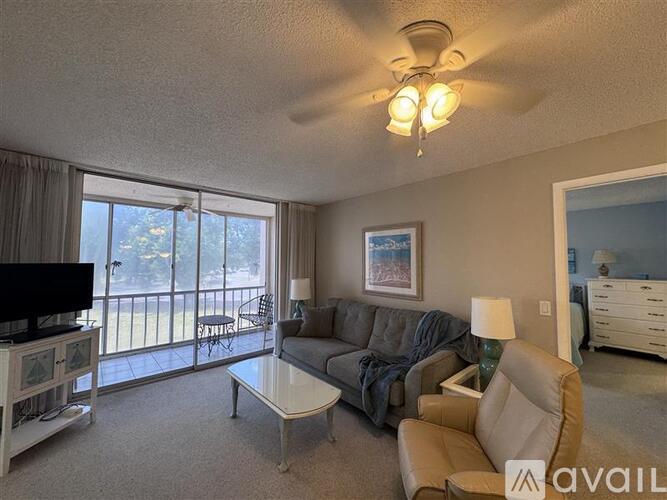 A living room with a grey couch, a coffee table, and a television.