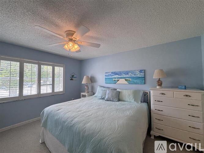 A bedroom with a bed, dresser, and ceiling fan.