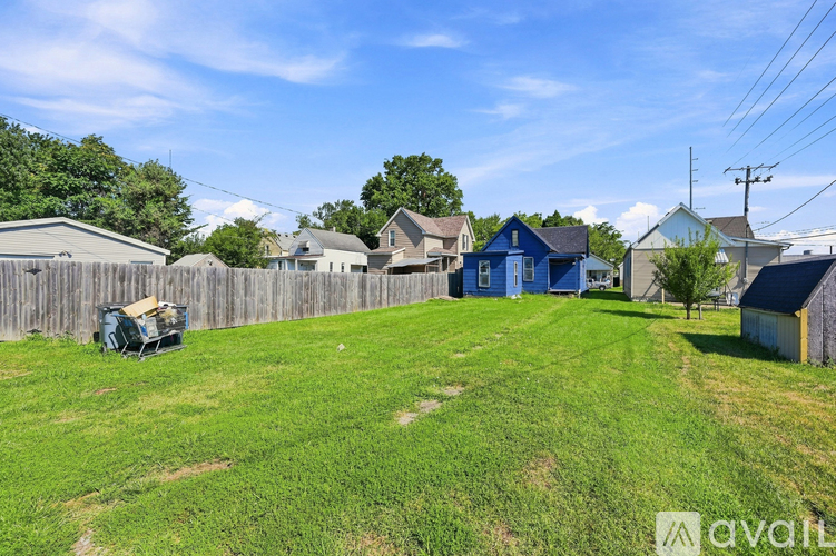 A grassy yard with a blue house and a wooden fence.