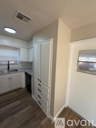 A kitchen with white cabinets and a wooden floor.