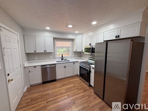 A kitchen with wooden floors and white cabinets.